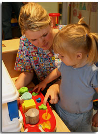 A nurse with a child playing with shape blocks